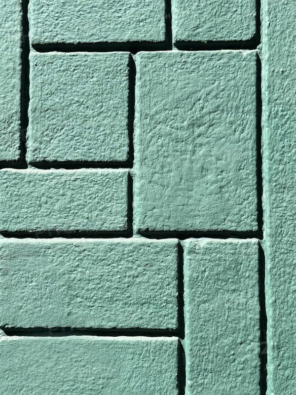 Detailed image of a green brick wall showcasing a geometric pattern. The textured surface and intricate design create an interesting visual effect ideal for modern backgrounds