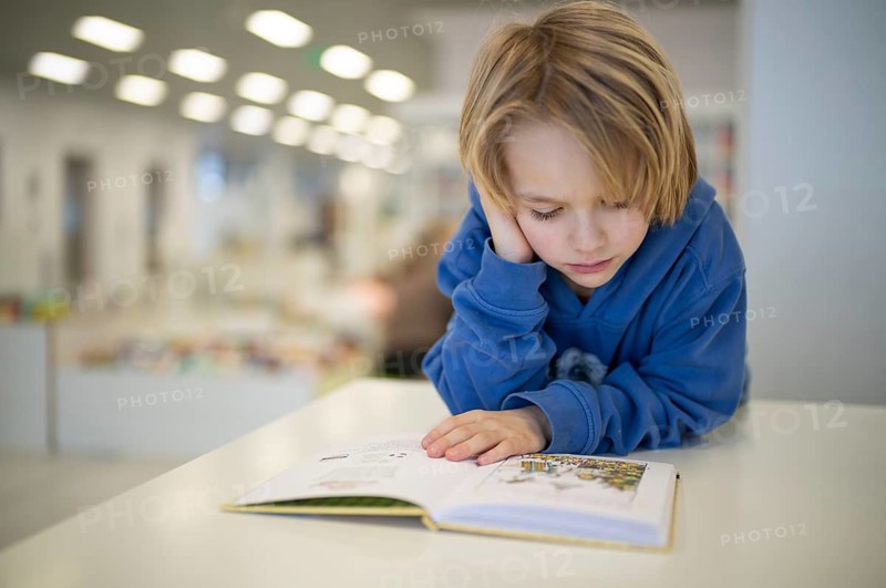 Interior shot, boy, 6 years old, blonde, reading book in the children's section of the city library, architect Eun Young Yi, Stuttgart, Baden-Württemberg, Germany