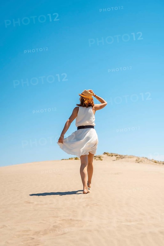 Vertical photo of an elegant woman in summer white dress on a dune in Cabo de Gata, Spain