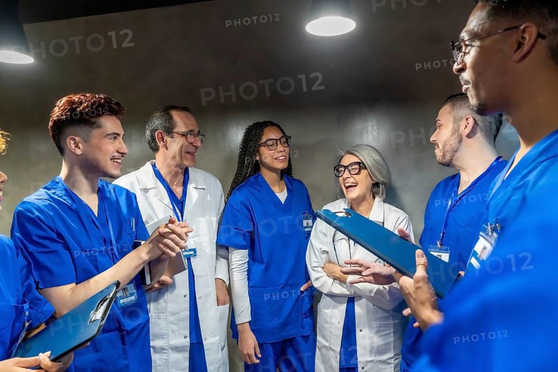 Diverse group of healthcare professionals laughing and discussing during a break, depicting teamwork, communication, and a positive working environment in medicine