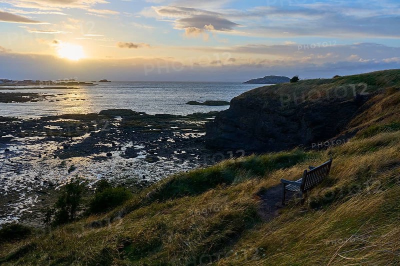 Lonely bench on a hill above rocky landscape with sunset sea view, North Berwick, East Lothian, Scotland, United Kingdom, Great Britain