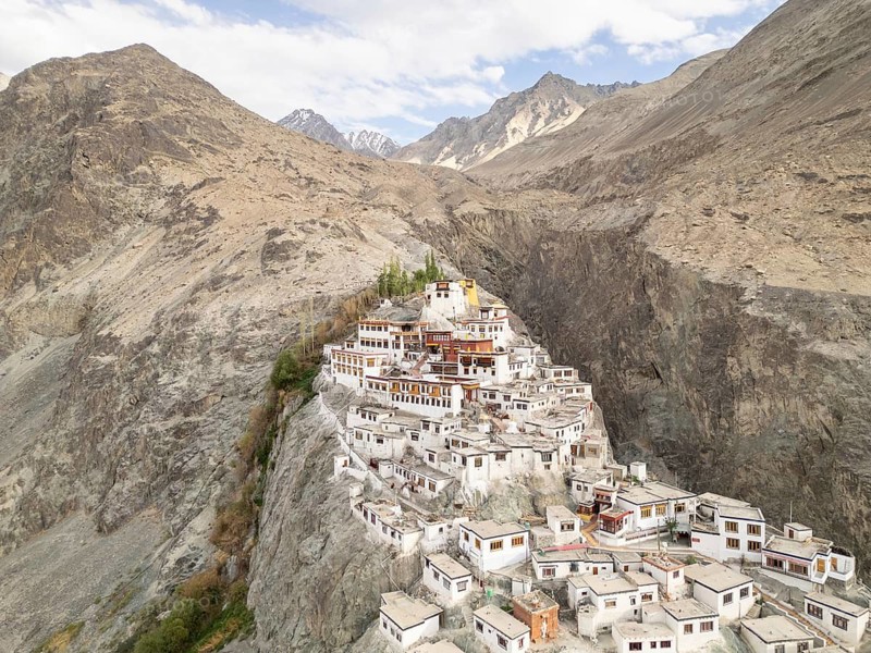 Aerial view of the historic Diskit Gompa Monastery, beautifully perched on a rocky hill in the Nubra Valley, India, surrounded by majestic mountains and a serene landscape