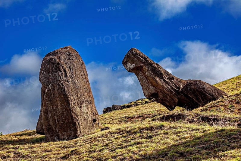 Two moai on a grassy hillside under a blue sky on Easter Island, The moai statues on Easter Island in the Pacific Ocean