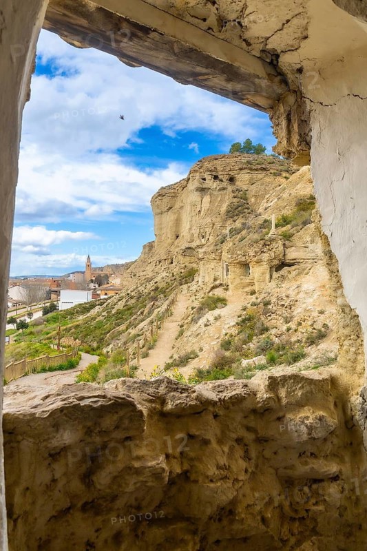 Breathtaking view of arguedas village and its cave houses carved into the sandstone cliffs, seen from a cave window in navarre, spain