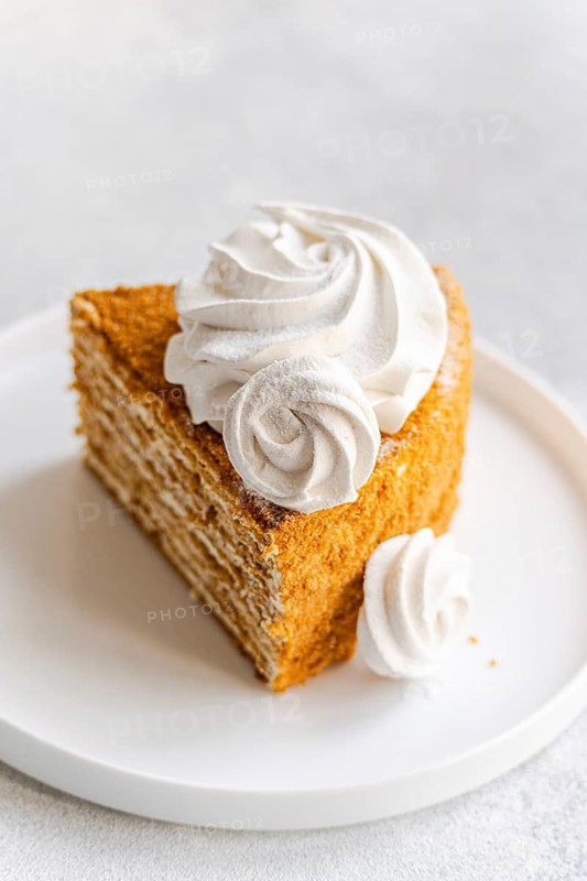 Tempting homemade honey cake topped with a luscious sour cream sauce and elegantly adorned with vanilla zephyr marshmallows, offering a delightful dessert experience