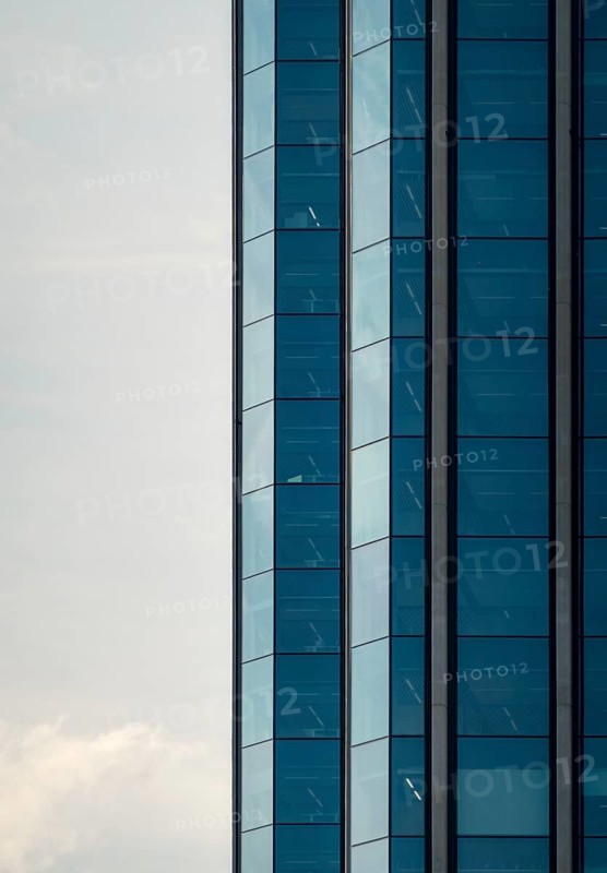 Close-up of a contemporary skyscraper featuring a blue glass facade, located in Colon City, Panama. This image captures the geometric details and reflections of the urban structure