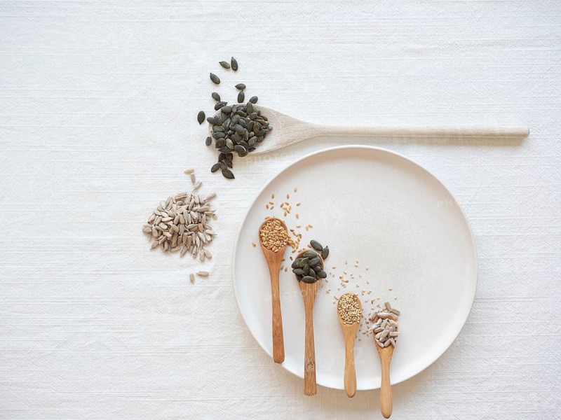 Different seeds on spoons and plate, promoting natural hormone balance