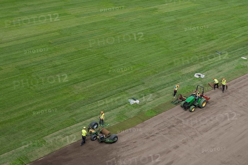 Workers laying grass in a roll on a football field at the stadium in Lubin, Poland