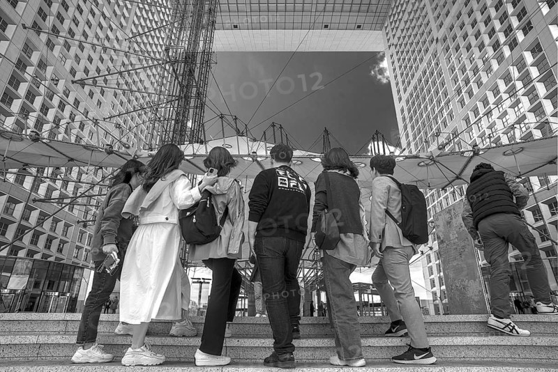 Tourists take a souvenir photo in the Grand Arche, La Défence, the New High City Quarter, black and white, Paris, France
