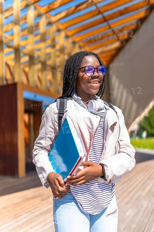 Vertical portrait of a cool african woman walking along university campus