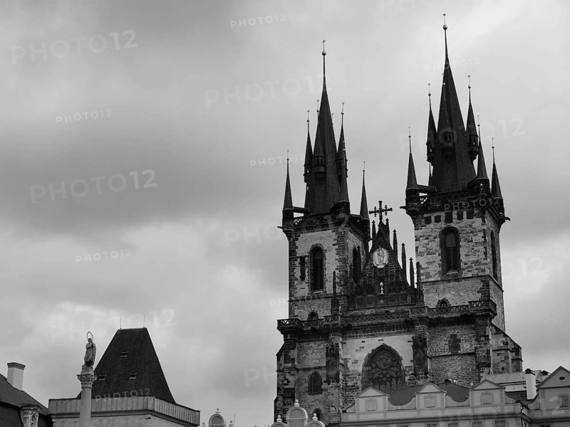 Tyn Church, Gothic church with distinctive towers and dramatic clouds in black and white, Prague