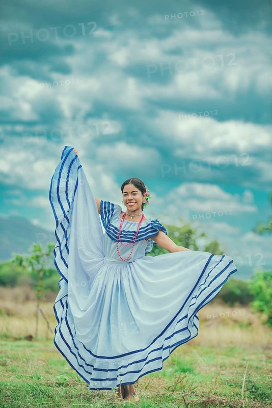Smiling yung woman wearing traditional Nicaraguan folk costume in a field. Happy girl in national folk costume in the field