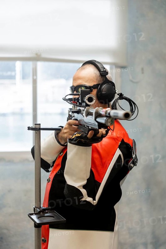 A talented blind athlete competes in an Olympic shooting event, using specialized equipment for precision and focus. The image showcases determination and adaptive sports technology