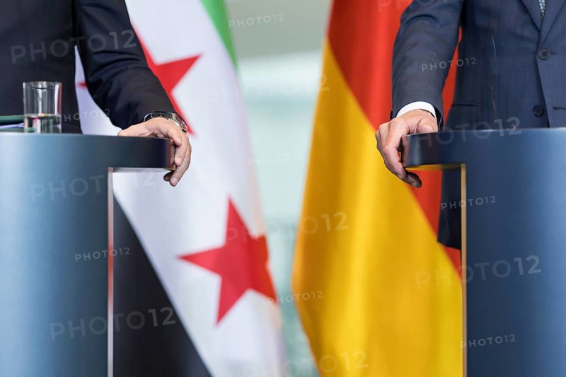 Ahmed al-Sharaa (President of the Syrian Arab Republic) and Friedrich Merz (Chancellor of the Federal Republic of Germany, CDU) clasp their lecterns with their hands at a press conference after a one-on-one meeting in the Federal Chancellery, Berlin, 30 March 2026