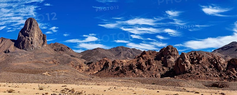Panoramic picture of a dry desert landscape with rocky mountain and blue sky, The landscape of the Ahaggar Mountains in the Sahara in Algeria