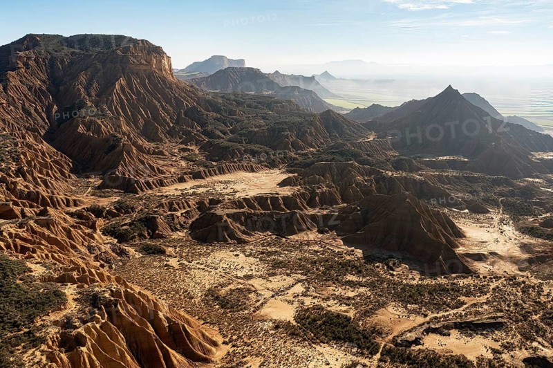 Captivating aerial view of a rugged mountain landscape featuring dramatic peaks and deep valleys The scene captures the vastness of nature with its layers of geological formations