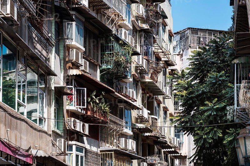 A detailed view of older buildings in Macau featuring barred balconies, designed for security, storage, and typhoon protection