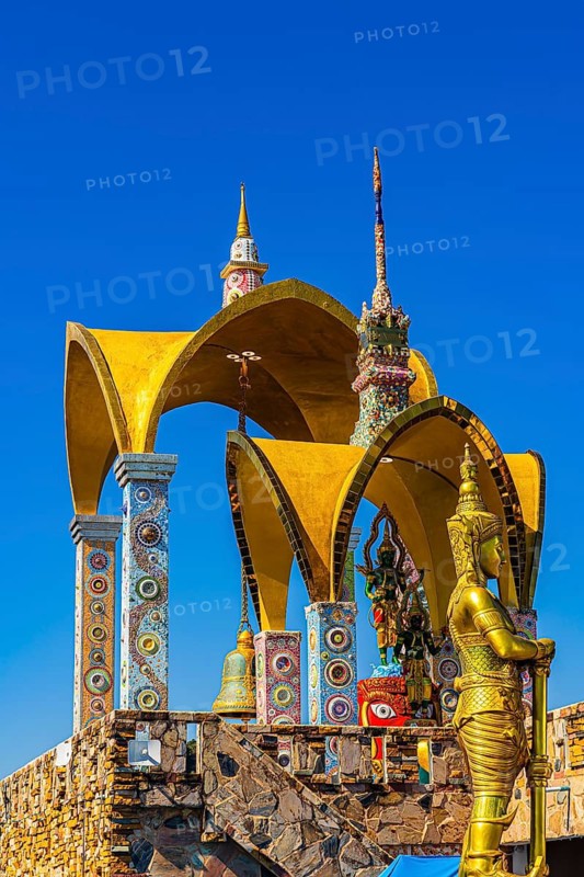 Round arch pavilions decorated with colorful mosaics and glass works of art, in front of a gilded temple guard, Buddhist temple complex Wat Phra That Sorn Kaew, Phetchabun province, Thailand