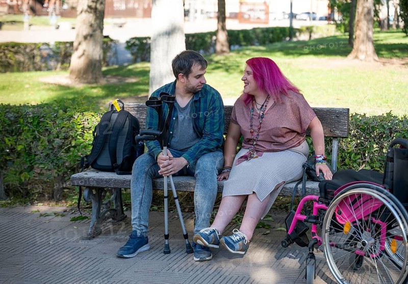 A college couple sitting on a bench embraces inclusivity and disability awareness The woman, affected by spina bifida, engages warmly with her partner, showcasing support
