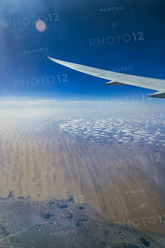 Above the clouds over Oman. View of the desert from the aircraft window during a flight from Phuket to Abu Dhabi with Etihad airline. Wing of a Boeing 787 aircraft. Abu Dhabi, United Arab Emirates, UAE, Southwest Asia
