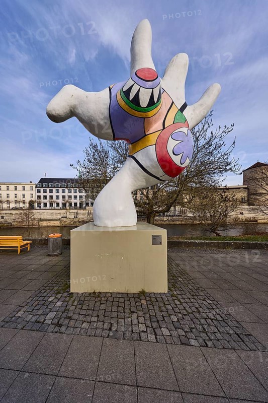 Nana, sculptor Niki de Saint Phalle, polyester sculpture, bench, public rubbish bin, riverside promenade, river Leine, general architecture, Begin Tower, city fortification, defence defence tower, diffuse light, milky blue cloudy sky, slightly sunny, Mike-Gehrke-Promenade, Hanover, state capital, Hanover region, Lower Saxony, Germany