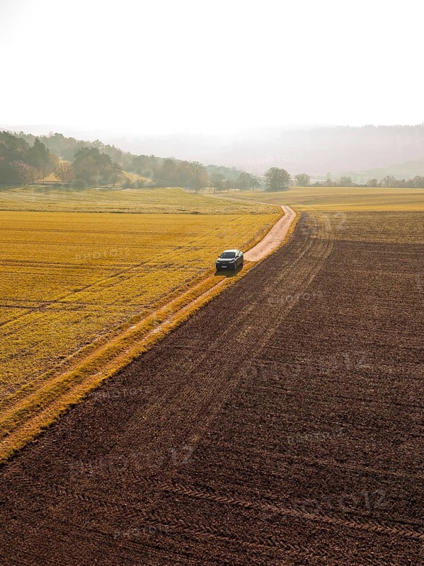 A car drives along a country lane, surrounded by autumnal fields and golden countryside, electric car VW ID5, Deer Carsharing, Gechingen, Black Forest, Germany