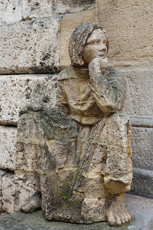 Sculpture in front of the old school building, art in public space, stone figure, sculpture by the artist Ulla Frenger, depiction of a schoolgirl, building from 1867 made of Gönningen tuff, former elementary and secondary school, today Gönningen town library branch, Gönningen, district of Reutlingen, Baden-Württemberg, Germany