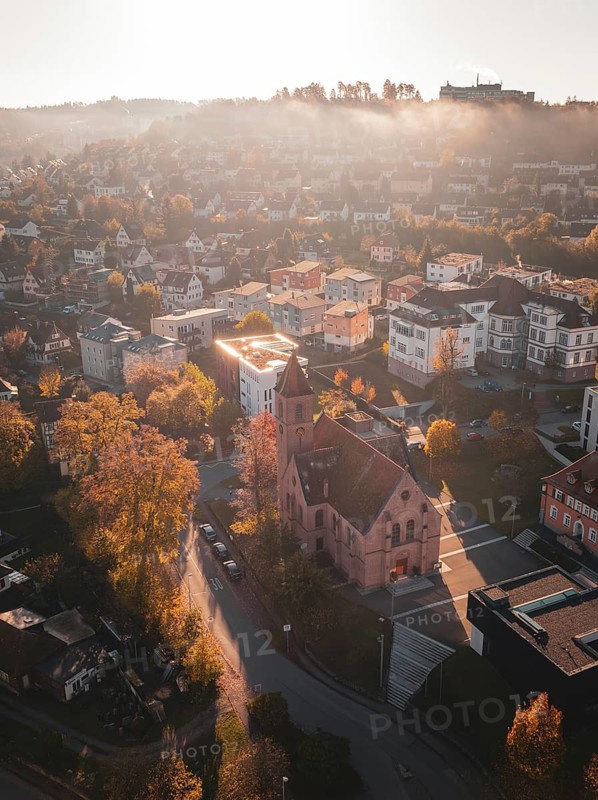 Church in the middle of an urban landscape at sunrise with autumnal colours, Nagold, Black Forest, Germany