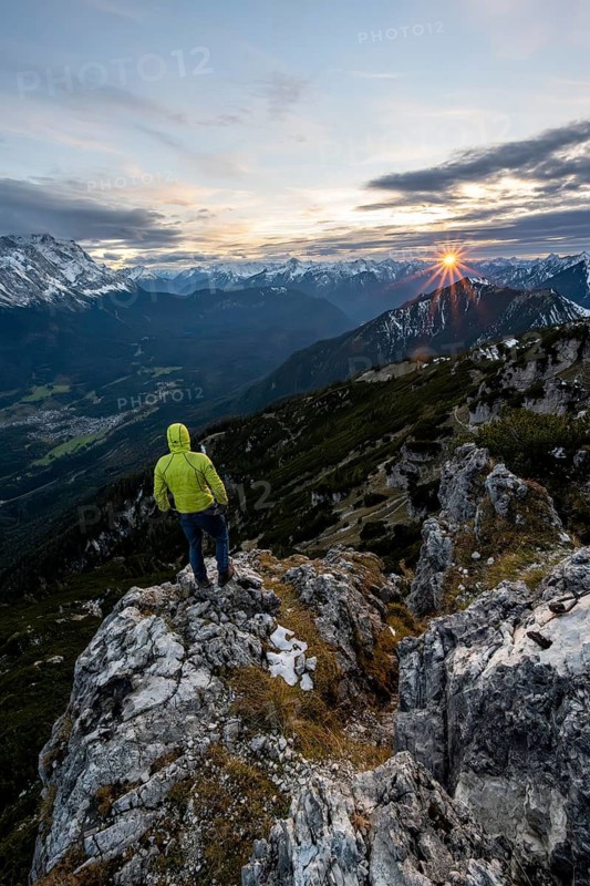 View Mountain panorama at sunset with sun star, mountaineer at the summit of the Kramerspitz, in autumn, Ammergau Alps, in autumn, Bavarian Prealps, Bavaria, Germany