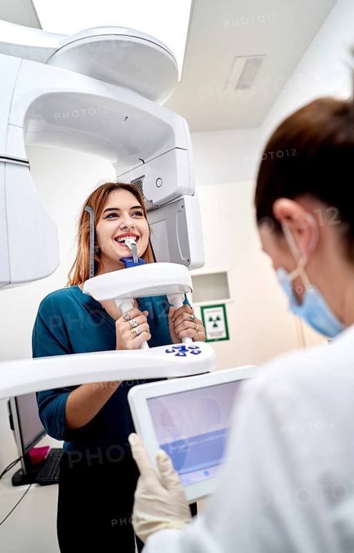 A patient undergoing a dental imaging procedure in a modern clinic. The scene captures advanced dental technology with a professional attending to the process