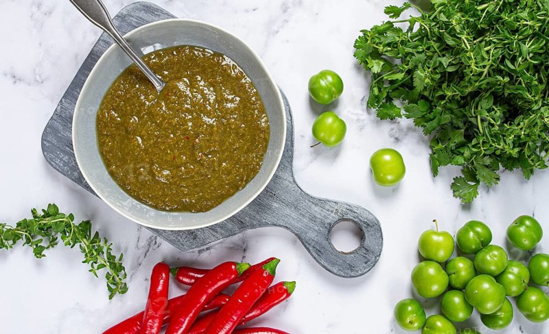 Tkemali sauce, made from green cherry plum, with ingredients on the table, top view, Georgian cuisine, no people