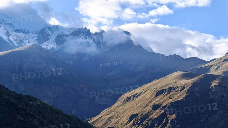 Majestic mountain landscape with clouds and sunlight in the background, Kazbek, Stepantsminda, Georgia