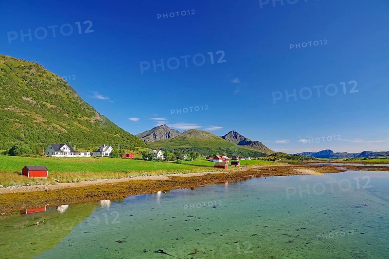 Clear water reflects the small village and surrounding mountains under clear skies, Leknes, Vestvågøya, Lofoten, Nordland, Norway