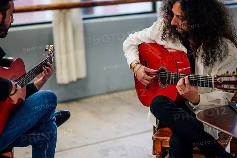 From above male friends playing guitars at table in music studio
