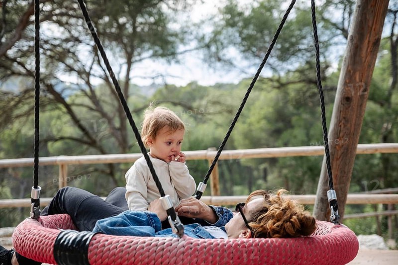 A mother and her daughter relax in a park in the forest during a peaceful afternoon. Surrounded by trees, they share a tender moment connecting with nature