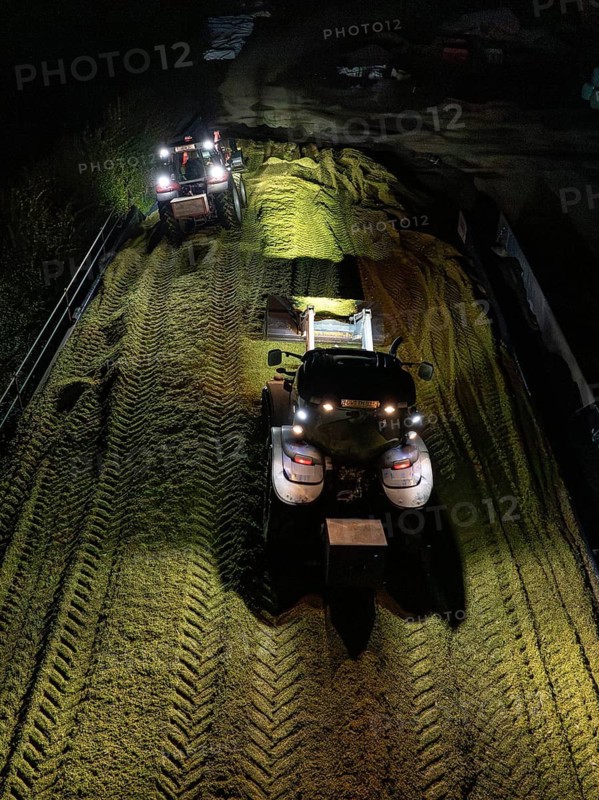 Two tractors working at night with their headlights switched on in a rural field, maize harvest, Dachtel, Black Forest, Germany