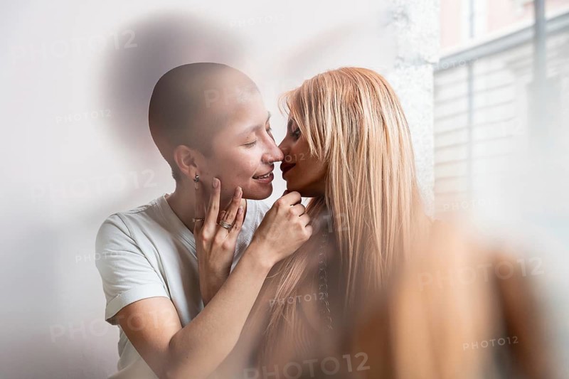 A tender moment shared between a loving lesbian couple, captured in a soft focus portrait. Their affectionate gaze exudes warmth and connection