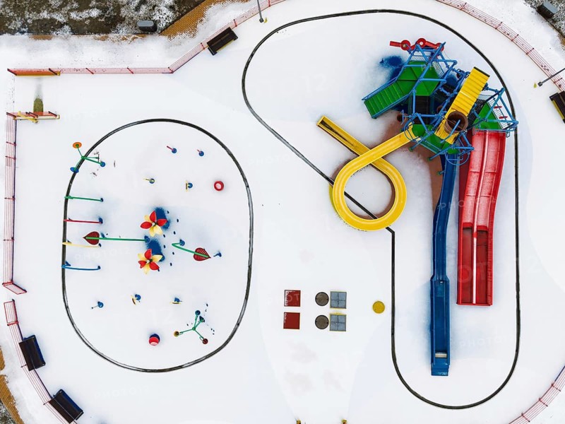 Minimalist top-down drone shot of colorful pool slides and equipment standing out against a clean, white, snow-covered ground in Lubin, Poland