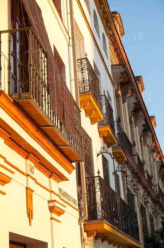 Late afternoon golden sunlight falling of historic houses in Placentines street, central Seville, Spain