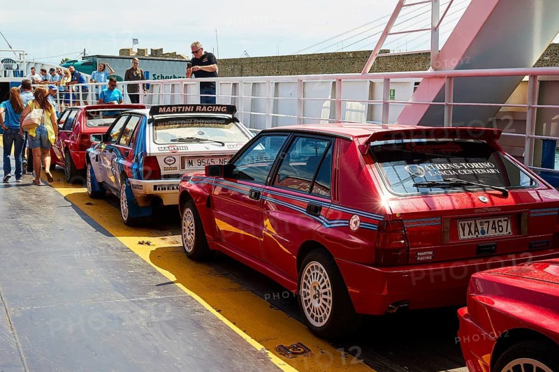 Several red vintage cars on a ferry surrounded by people under a bright sky, rally cars, Rio-Antirrio ferry, cable car bridge, Gulf of Corinth, Patras, Peloponnese, Greece