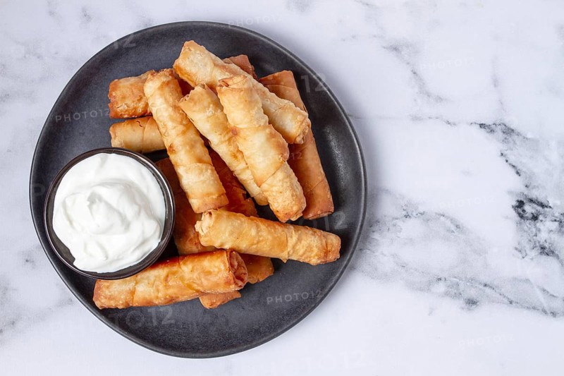 Fried spring rolls with cheese, on a plate, with cream sauce, no people