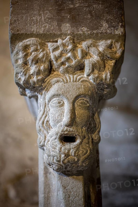 Close-up of a Romanesque stone relief on a capital in the crypt of Constance Cathedral showing a bearded man's face with a wide open mouth in an expressive, antiquing form, Constance, Konstanz district, Baden-Württemberg, Germany