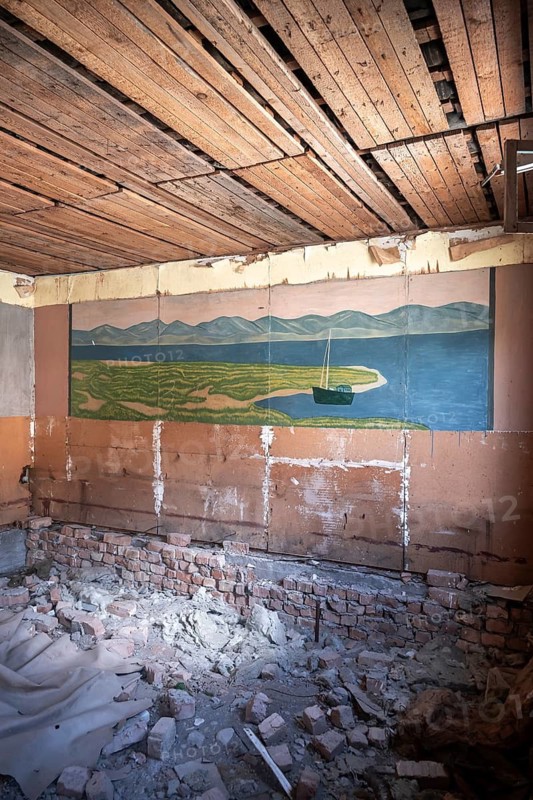 Destroyed abandoned classroom of the old school, wall painting of Kyrgyz landscape, ghost town, Engilchek, Tian Shan