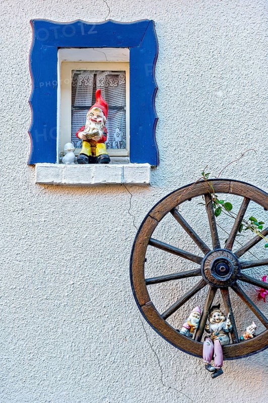 Garden gnomes on a small window and in a wooden wagon wheel on a house wall, decoration, Steinau an der Straße, Hesse, Germany