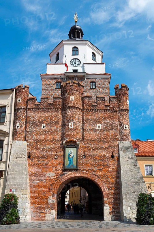 An imposing brick city gate with decorative elements under a blue sky, Krakow Gate, Brama Krakowska, Lokietka Square, Lublin, Poland
