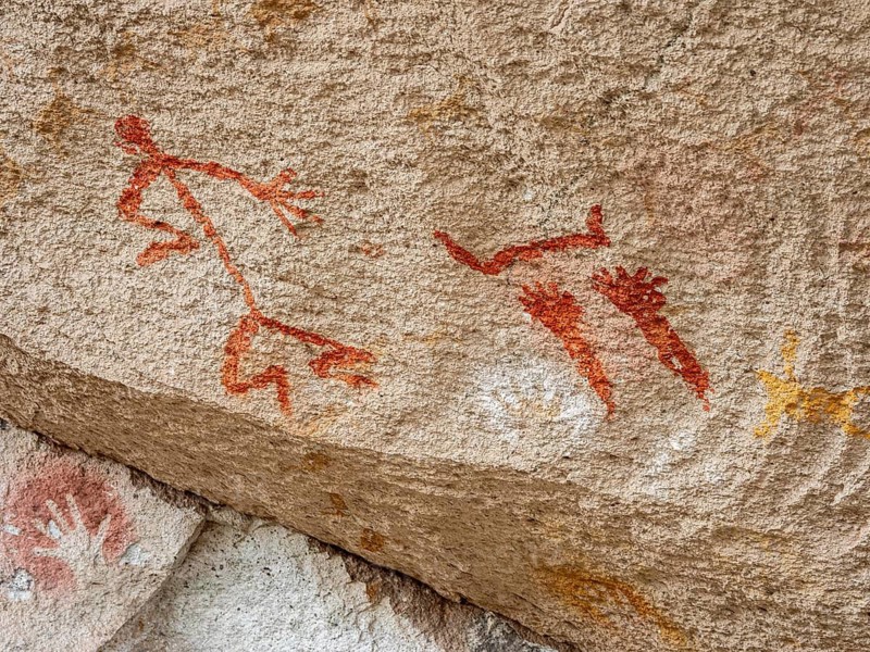 Colored hands and painted human being at the wall of the canyon, Cueva de las Manos, prehistoric paintings, Unesco world heritage, Argentina