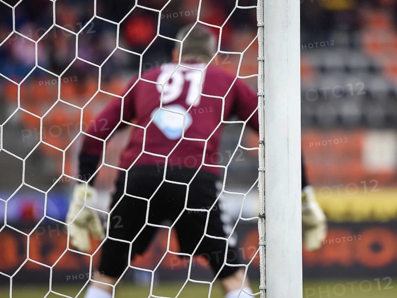 Detail of goal's post with net and football goalkeeper in the background.
