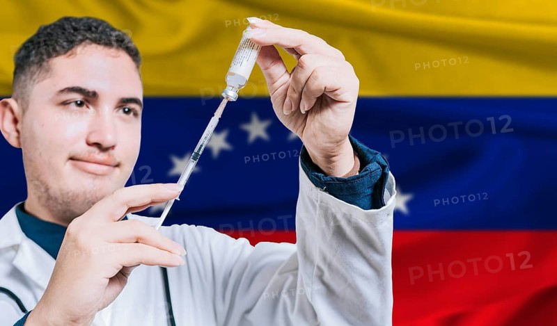 Doctor holding syringe on Venezuela flag background. Medical professional holding syringe with Venezuelan flag in the background