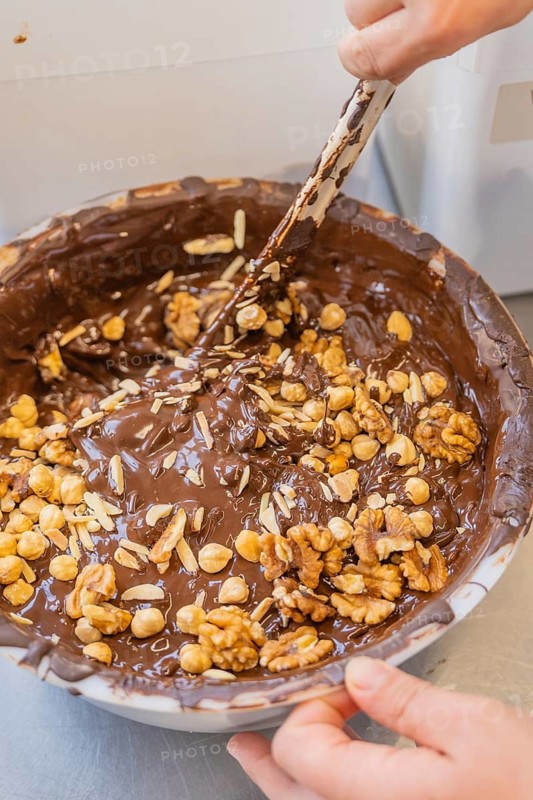 A large bowl contains melted chocolate and various nuts that are mixed together, Production Burch Schokolade, Haselstaller Hof, Gechingen, Germany