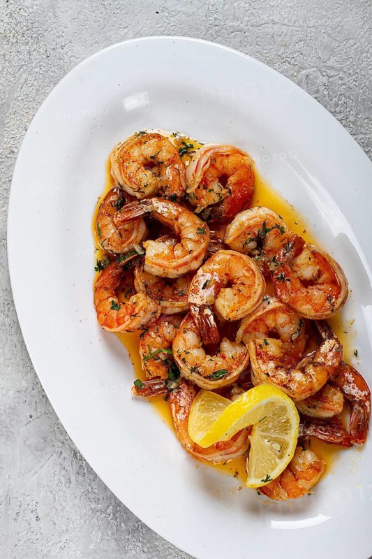 Fried tiger prawns, jumbo, in garlic sauce, in butter, with herbs, on a white plate, homemade, no people